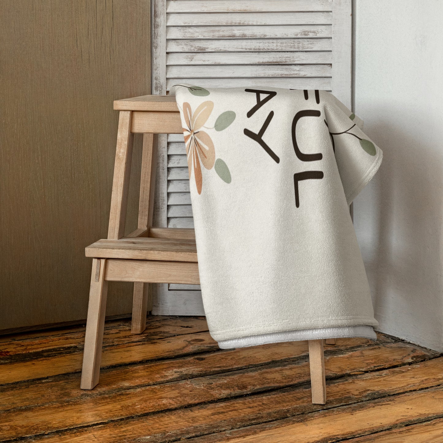 A beige floral towel draped over a wooden stool in a rustic interior setting