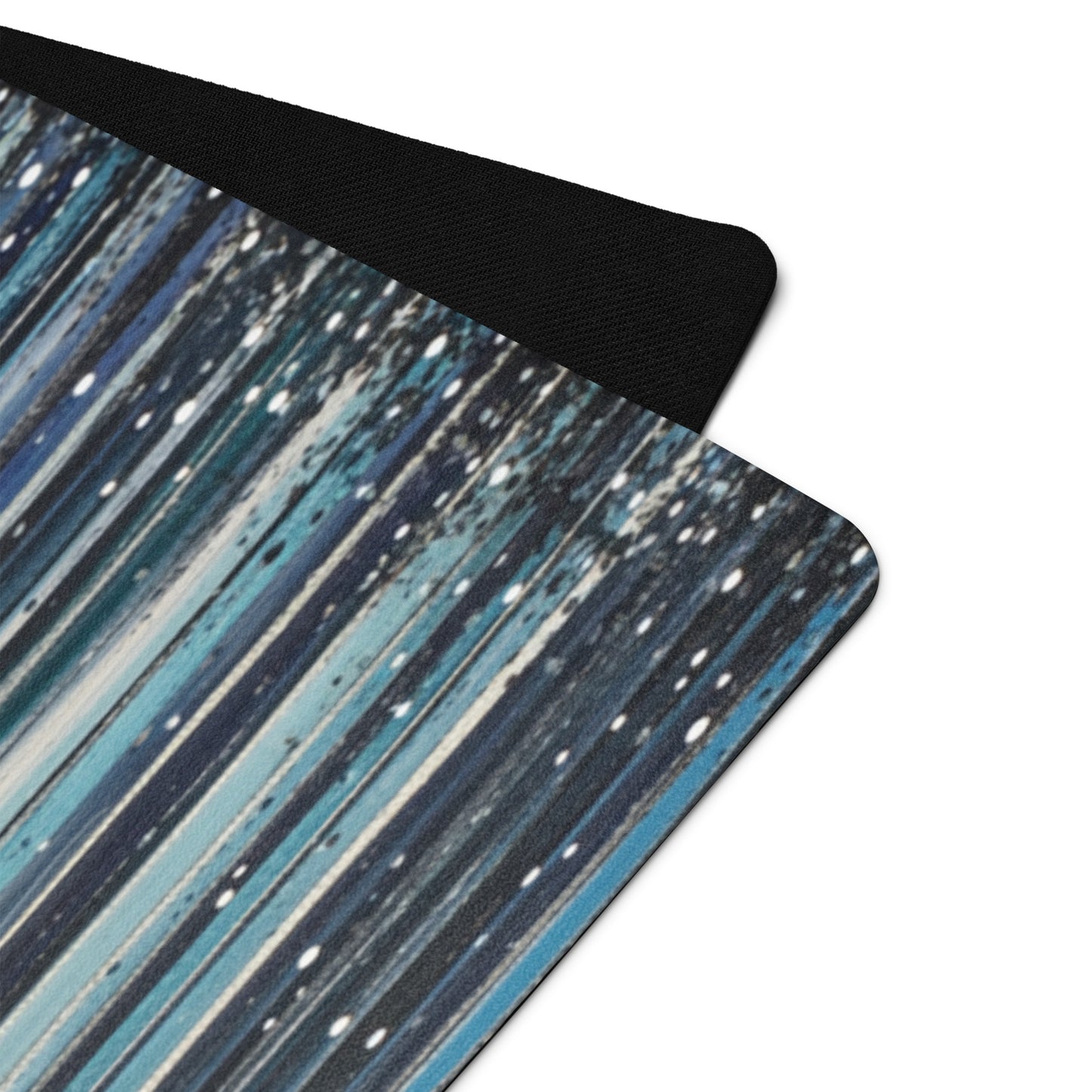 A close-up of a yoga mat showcasing a blue and black streaked design with fine white speckles, highlighting its texture and material quality