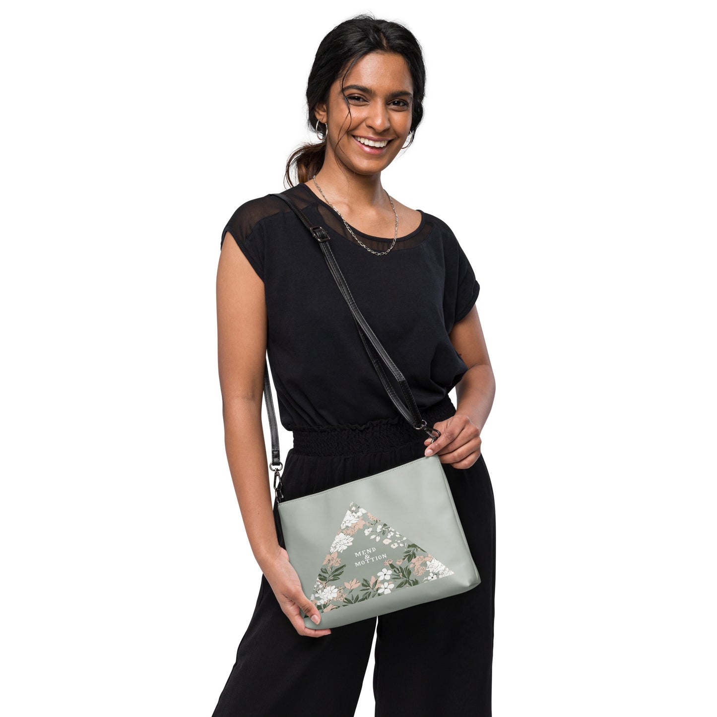 Stylish crossbody bag with a floral triangle design, worn by a smiling woman in a black outfit, featuring a sleek black strap