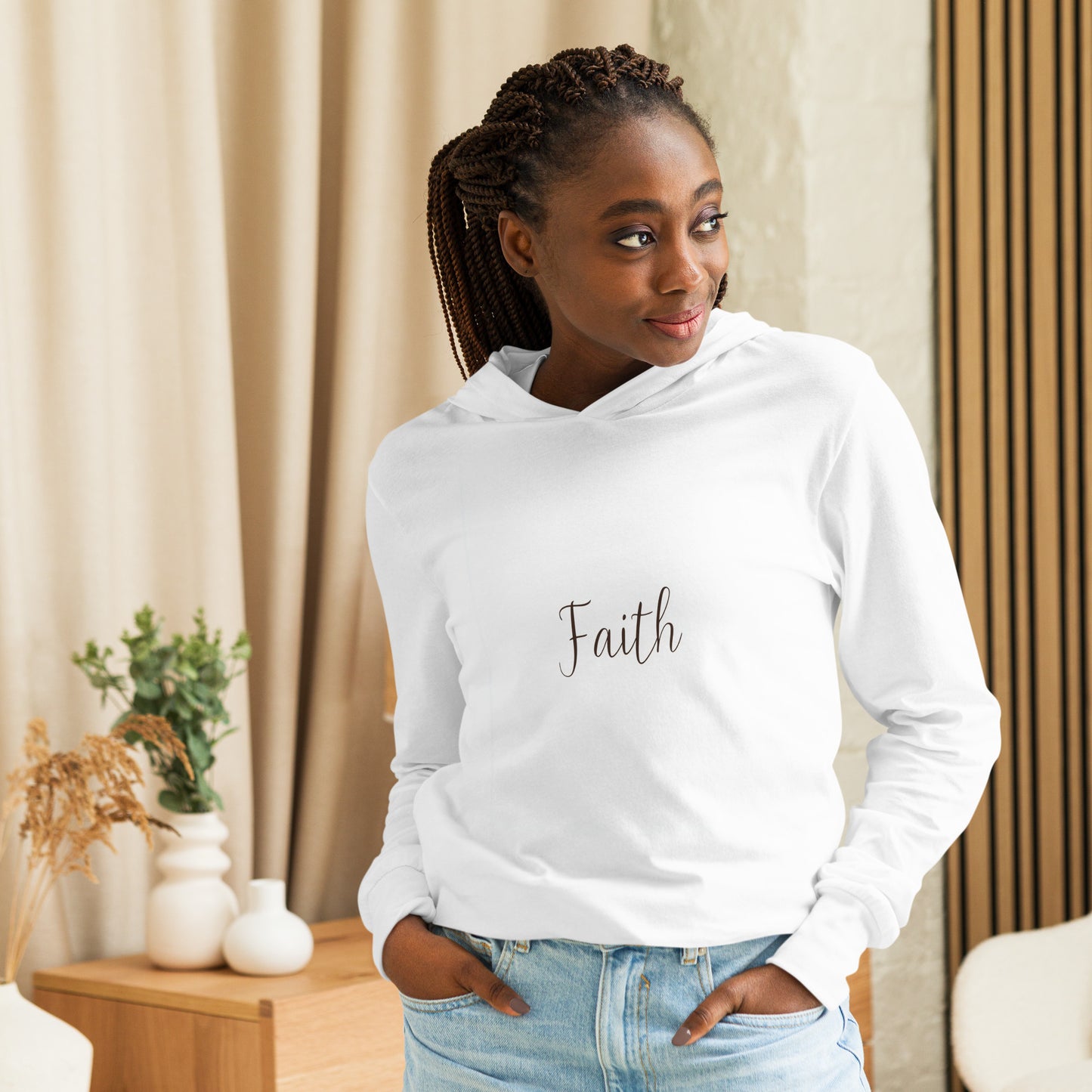 Woman in white Faith long-sleeve hoodie smiling indoors with natural lighting.
