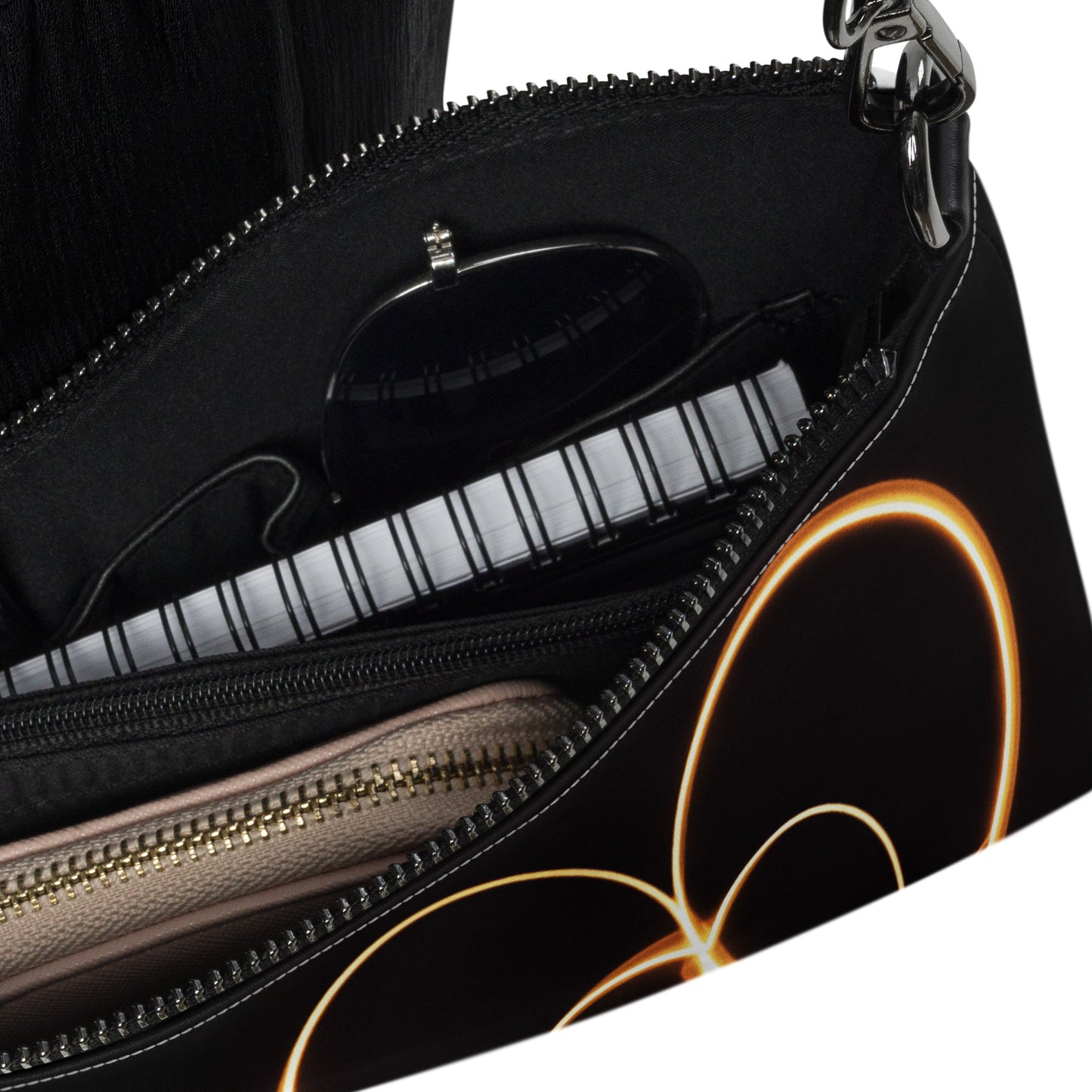 Close-up of the interior of a black crossbody bag with compartments and glowing heart design visible on the side