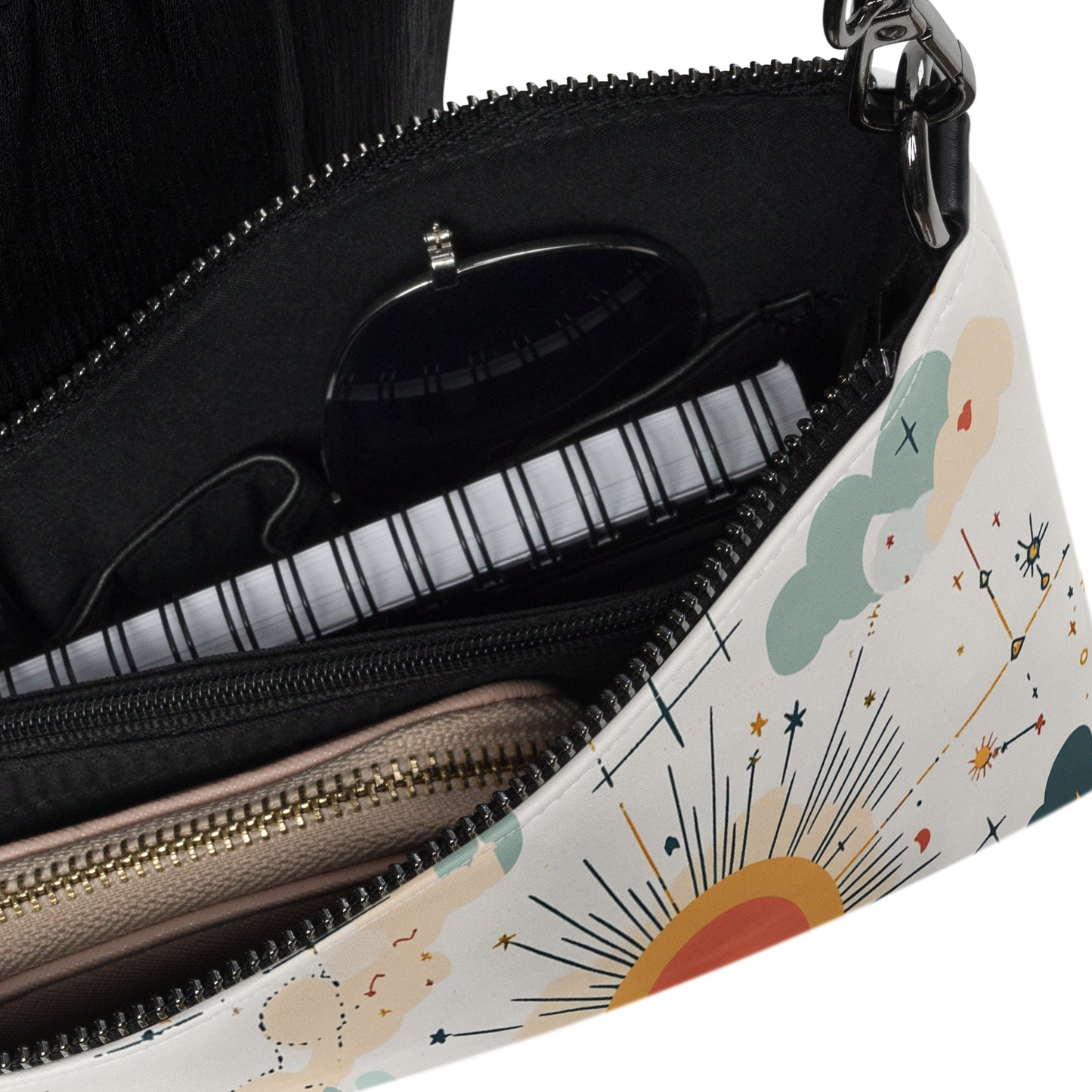 Close-up of crossbody bag interior showcasing compartments holding a wallet, notebook, and sunglasses