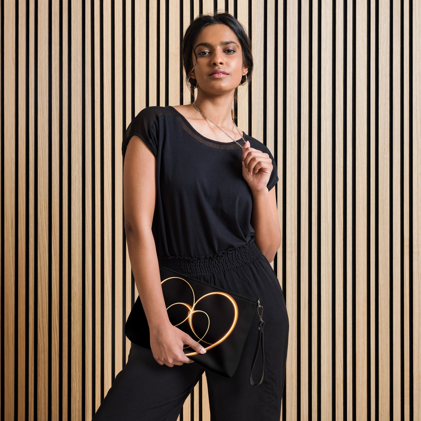 Woman holding a sleek black crossbody bag featuring a glowing golden infinity design, adding elegance and mindfulness to her outfit