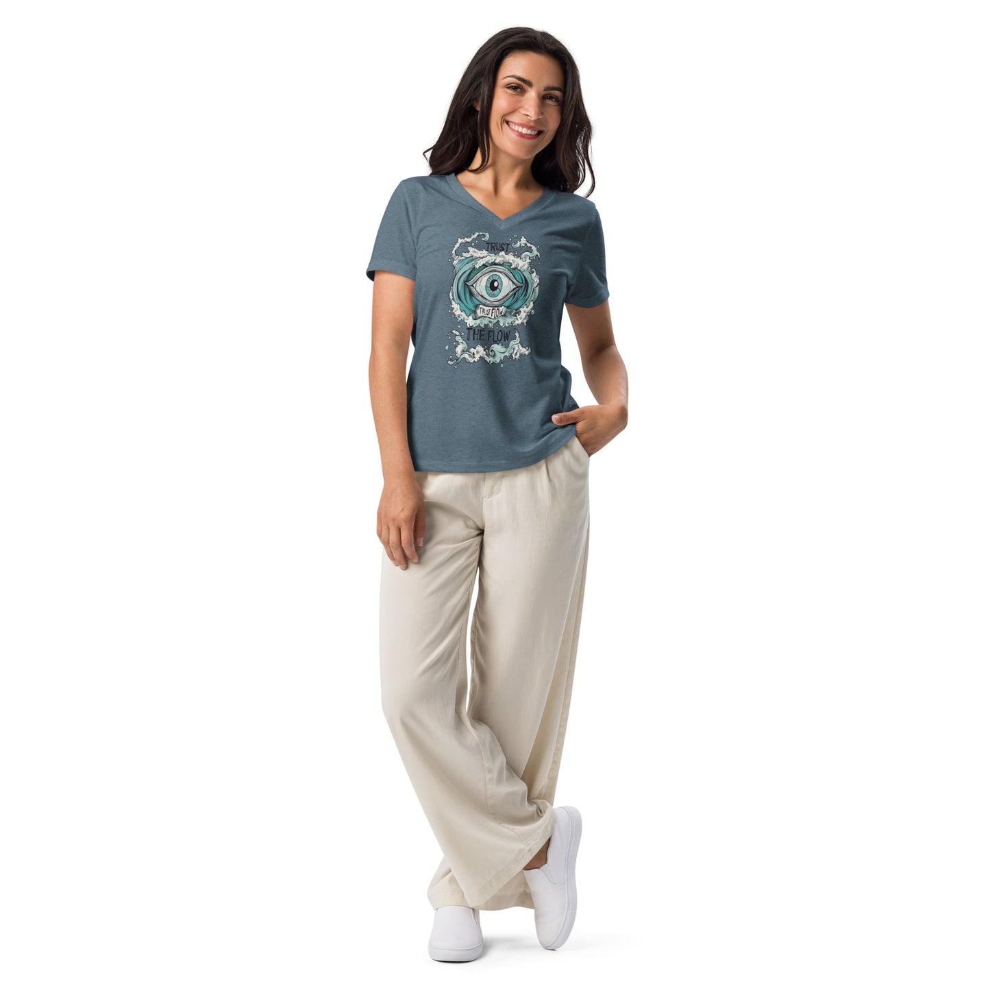 A woman wearing a heather slate V-neck T-shirt with an artistic eye design, paired with beige pants and white sneakers