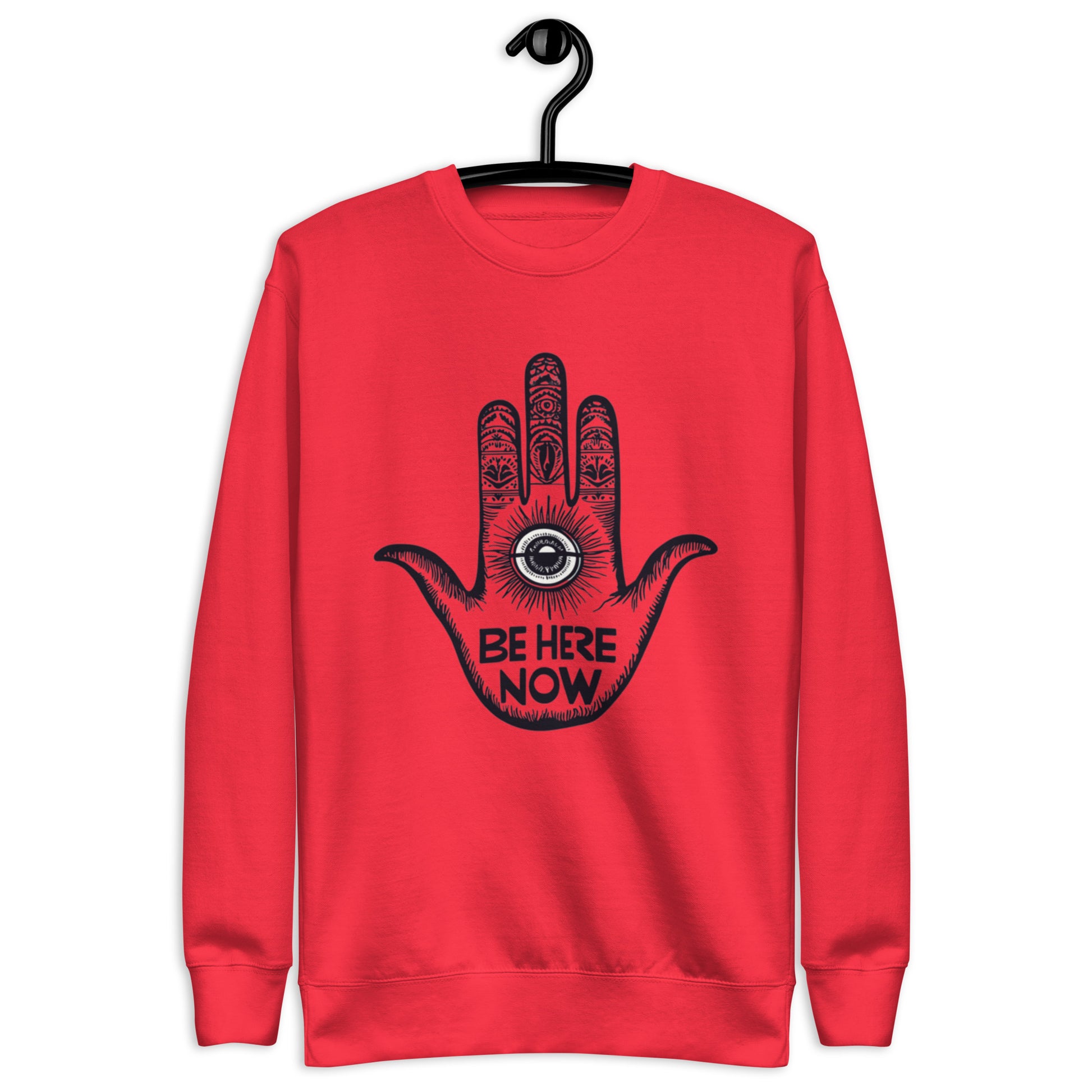 Red sweatshirt featuring a hand design with intricate patterns and the phrase 'Be Here Now' at the center