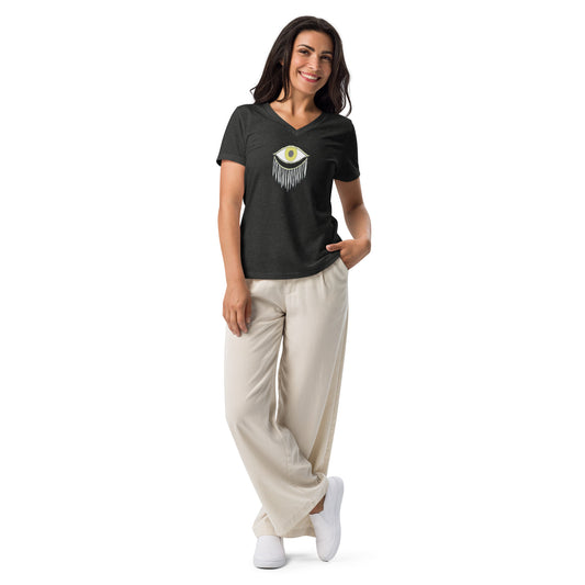 Model wearing a black V-neck T-shirt with an abstract eye and fringes design, paired with beige trousers and white sneakers