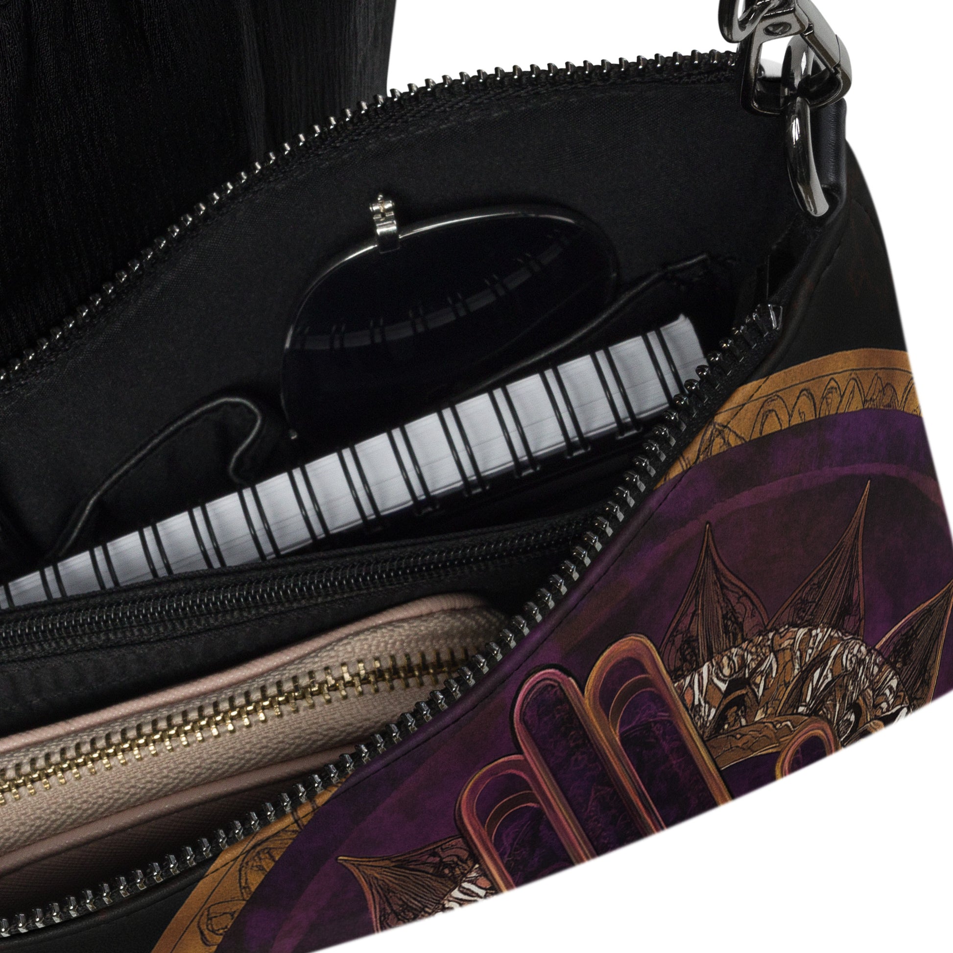 Close-up of a crossbody bag interior showing compartments and a glimpse of the artistic purple and gold design on the side