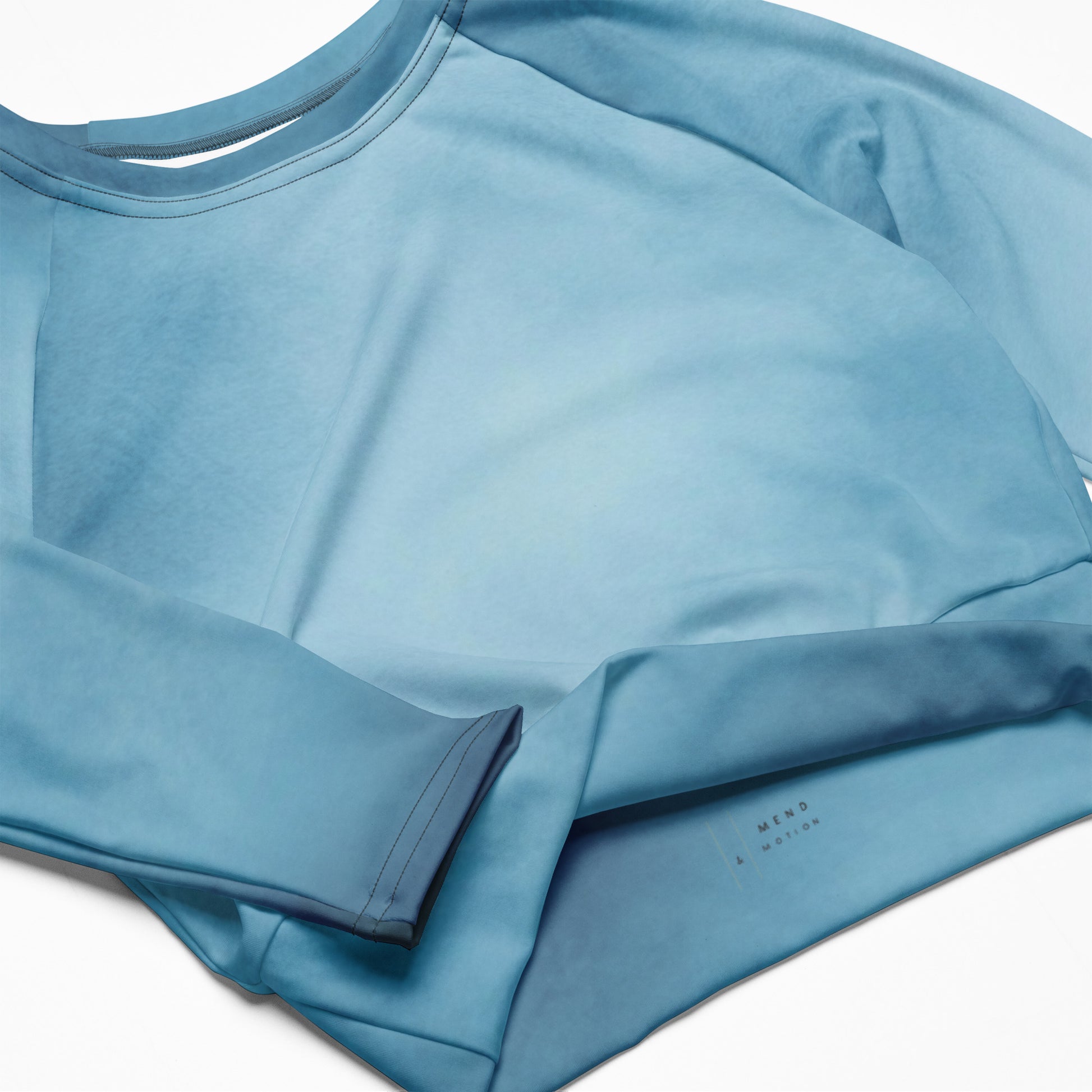 Flat lay of a blue long sleeve crop top with subtle fabric details, showing neatly folded sleeves and lightweight material