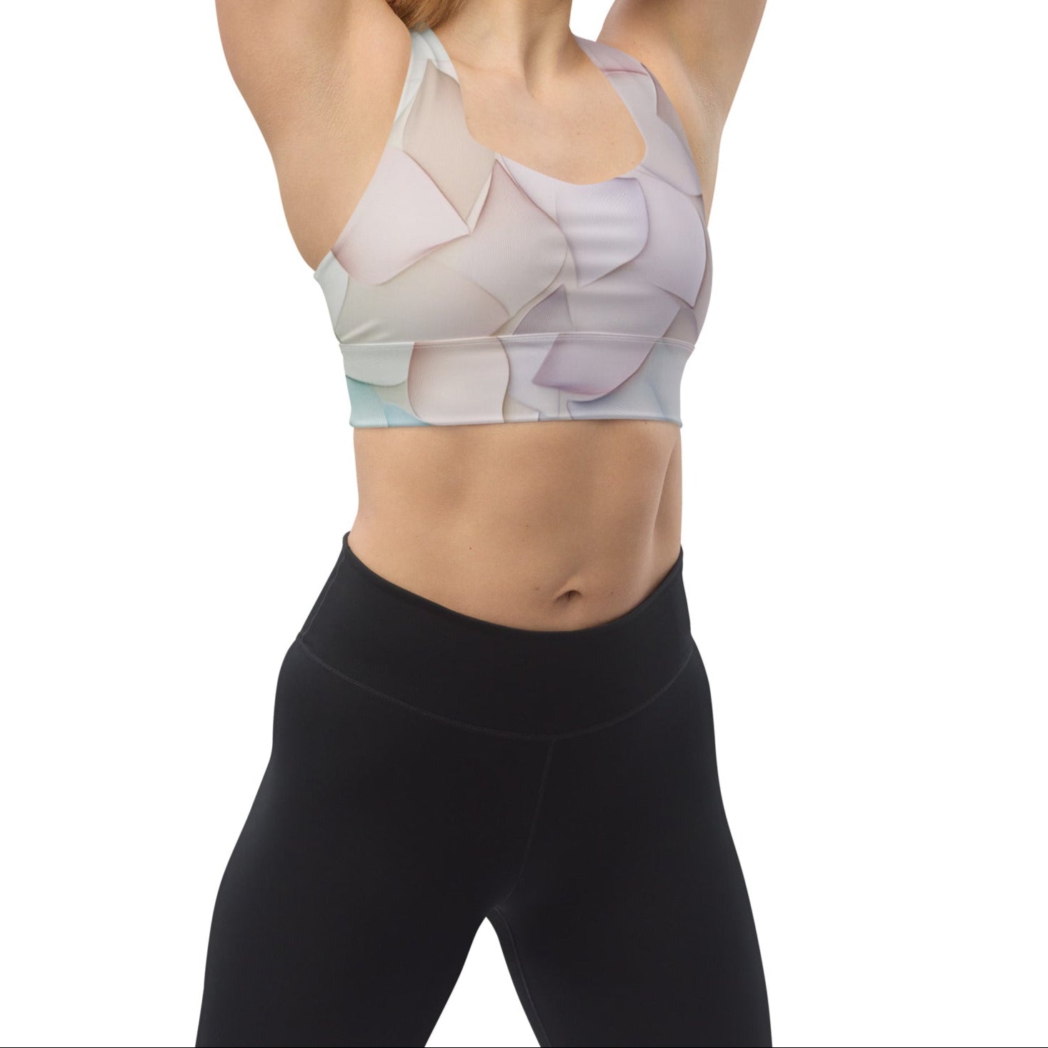A model wearing the Petal Bloom Longline Sports Bra with a pastel petal pattern, paired with high-waisted black leggings for a sleek workout look