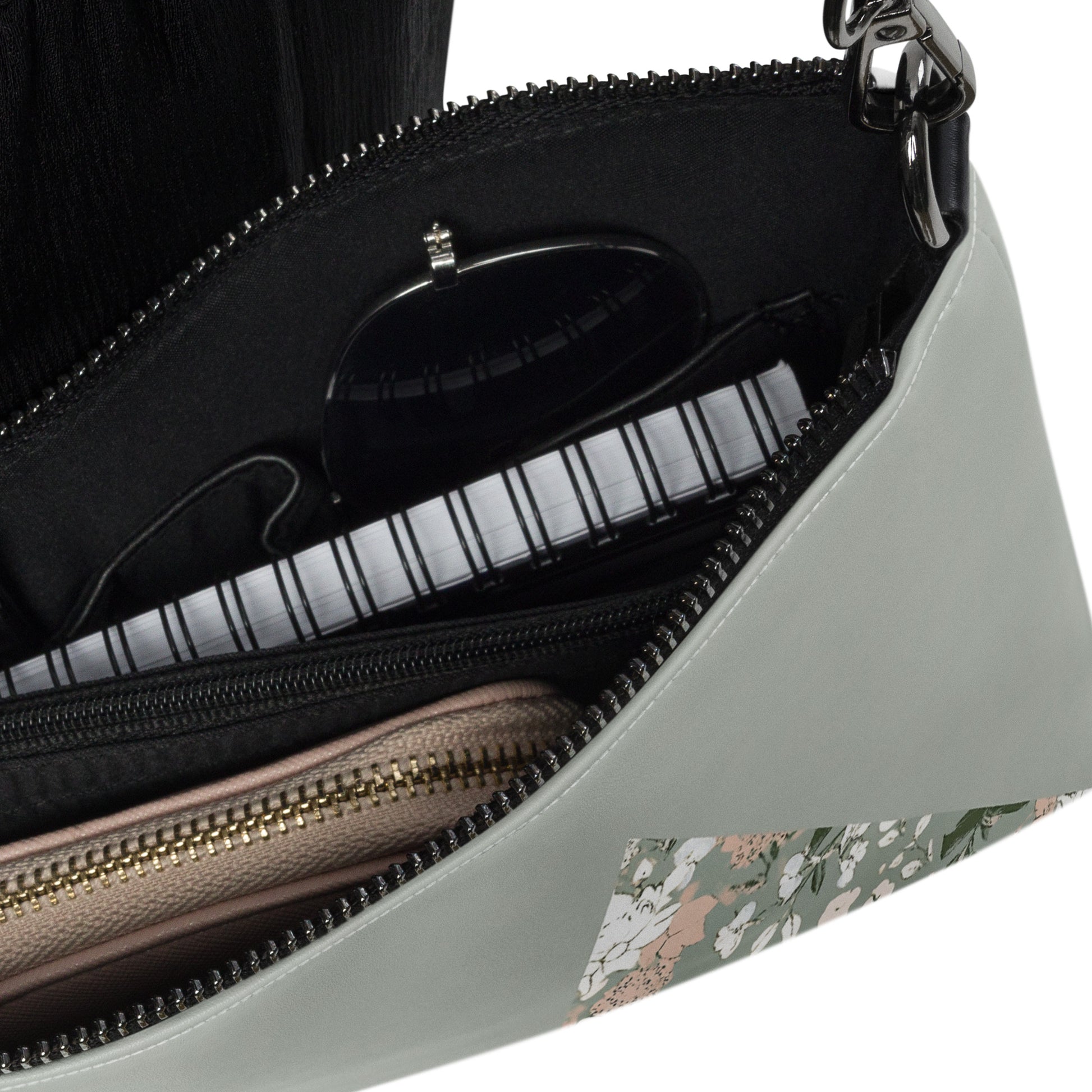  Close-up of a crossbody bag's interior, showing organized compartments holding essentials like sunglasses and a wallet