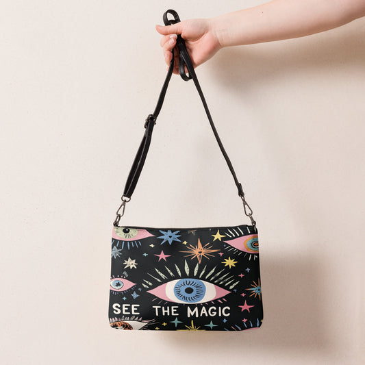  A black crossbody bag featuring colorful eye and star designs with the phrase 'See the Magic' on the front