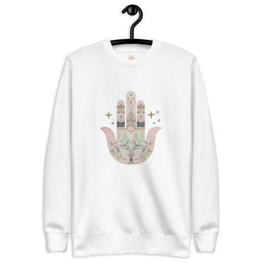 A white sweatshirt featuring a pastel-colored Hamsa hand design with floral and geometric elements, displayed on a hanger.