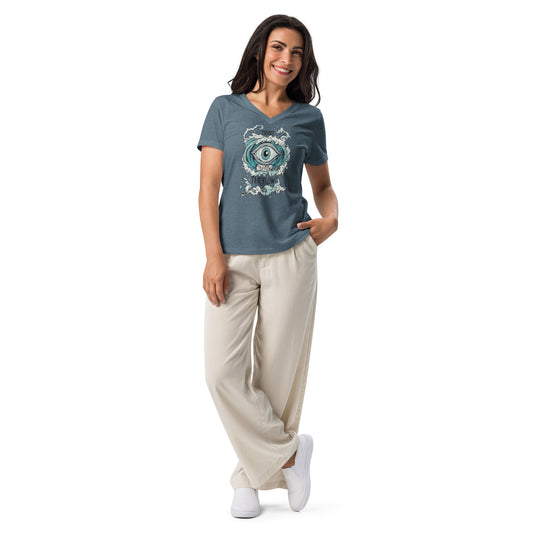 A woman wearing a heather slate V-neck T-shirt with an artistic eye design, paired with beige pants and white sneakers